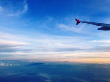 Airplane wing against sky during sunset