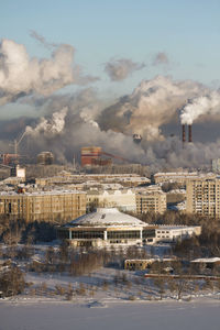 Smoke emitting from factory against sky during winter