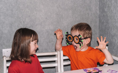 Children sit at the table and make decorations for the house for halloween.