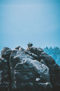 Low angle view of man standing on cliff against clear sky