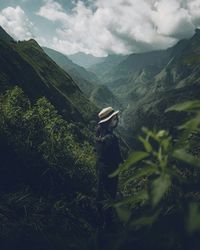 Woman standing amidst plants against mountains