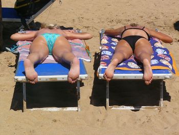 Rear view of female friends sunbathing at beach
