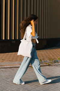 Full length of young woman standing against wall