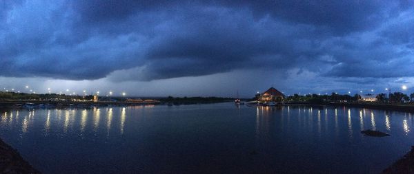 City buildings by lake against sky at night