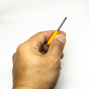 Close-up of man hand holding pencils against white background
