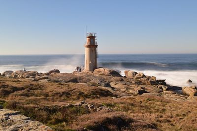 Lighthouse by sea against sky