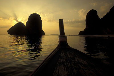 Silhouette rock in sea against sky during sunset