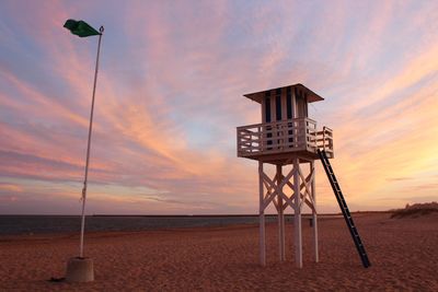 Lifeguard hut at beach against sky during sunset