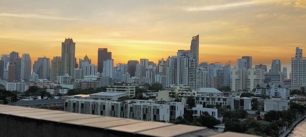 Modern buildings in city against sky during sunset