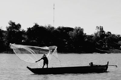 Silhouette people on boat against sky