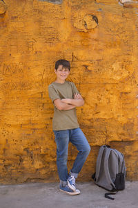 Portrait of young boy standing against yellow wall