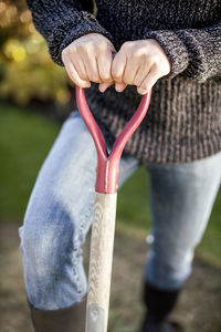 Midsection of woman holding shovel at garden