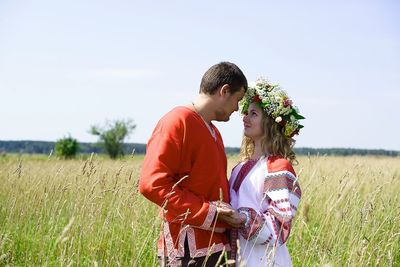 Side view of siblings standing on field against sky