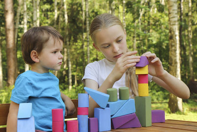 Siblings playing with toy blocks on table