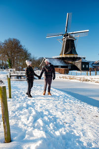 People on snow covered field against sky