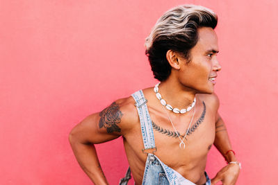 Young man looking away against pink background