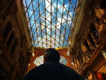 Low angle view of man standing by window in building