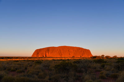 Rock formations on landscape against clear blue sky