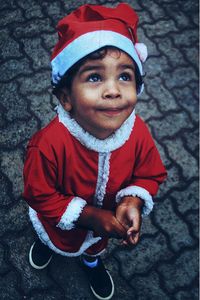 High angle view of cute boy in santa costume standing outdoors