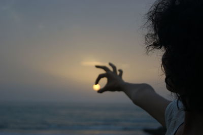Woman holding sun during sunset