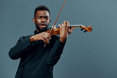 Man playing violin against blue background