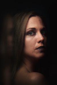 Close-up portrait of young woman against black background