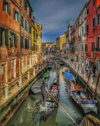 Canal amidst buildings in city against sky