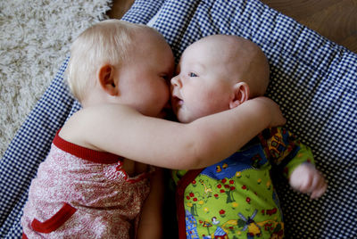 High angle view of siblings lying on fabric