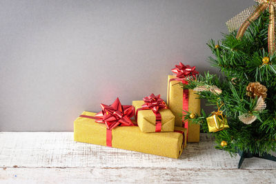 Close-up of christmas tree and presents against gray wall