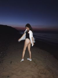 Full length of woman standing on beach against sky