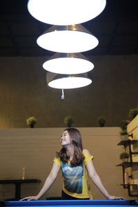 Smiling woman standing under illuminated pendant lights