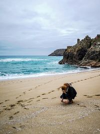 Full length of woman crouching on sand at beach