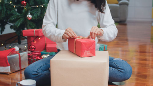 Midsection of woman holding christmas lights on table