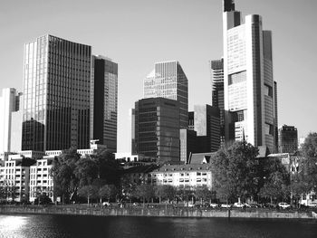 Modern buildings by river against sky in city