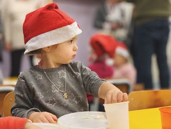 Cute girl wearing christmas hat while looking away