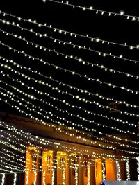 Low angle view of illuminated lights against building at night