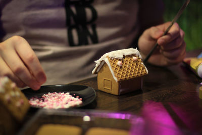 Midsection of man preparing gingerbread house