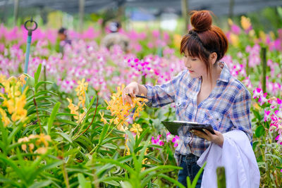 Rear view of woman with pink flowers on mobile phone