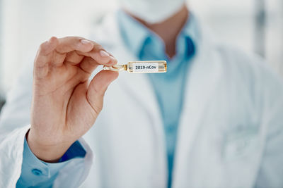 Midsection of doctor holding thermometer