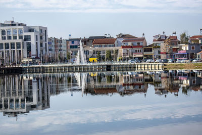 Reflection of buildings on river against sky