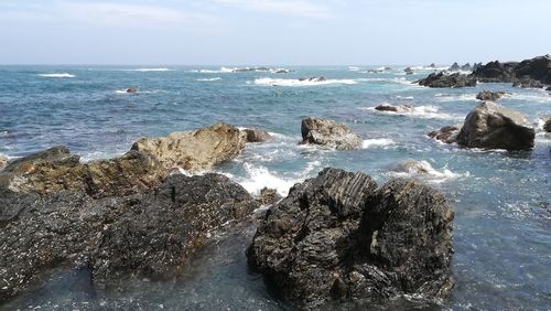 Rocks on sea shore against sky