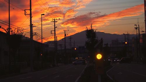 Vehicles on road against dramatic sky during sunset