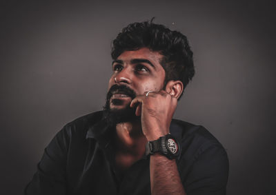 Young man looking away against black background