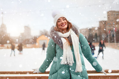 Portrait of smiling woman standing in snow during winter