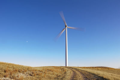 Wind turbine in motion against blue sky