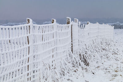A fence completely covered with snow in a snowy landscape in winter