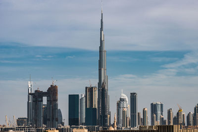 Burj khalifa in city against cloudy sky