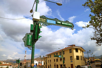 Low angle view of road sign by buildings against sky