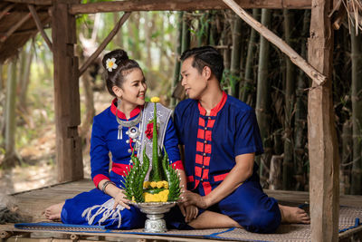 Full length of father holding girl sitting outdoors