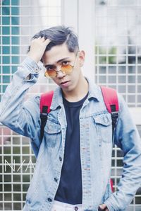 Portrait of young man standing against metal fence